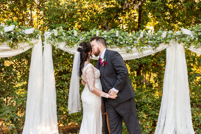 november wedding couple kissing at altar decorated with white chiffon and greenery