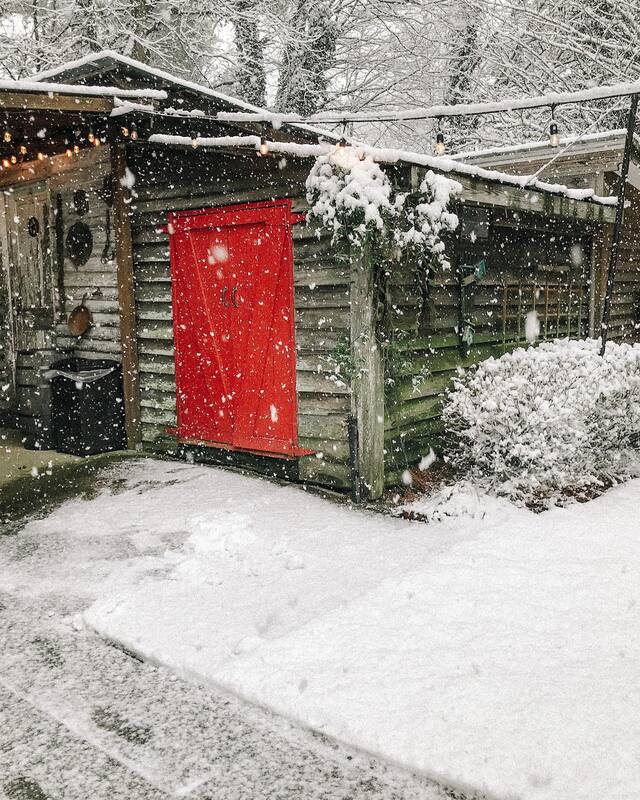 red doors at smokehouse during winter snowfall