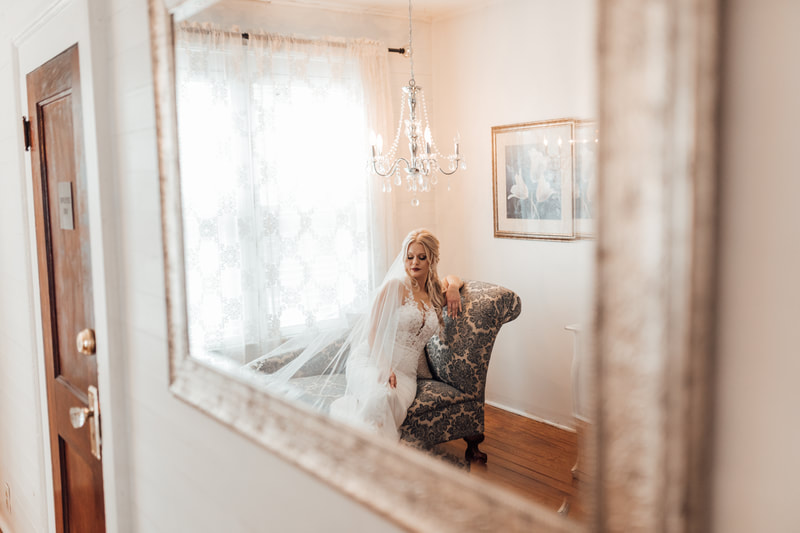mirror reflection of bride sitting on chaise lounge 