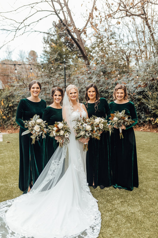 bride posing with bridesmaids in velvet emerald green dresses
