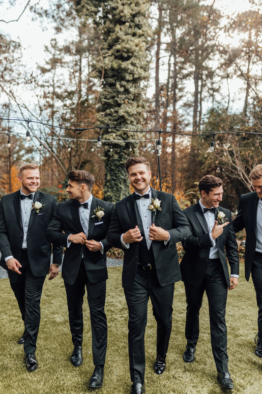 groom and groomsmen walking in garden venue wearing matching black suits