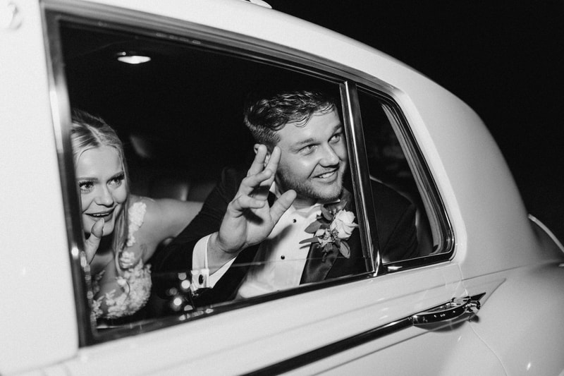 black and white photo of bride and groom in vintage getaway car