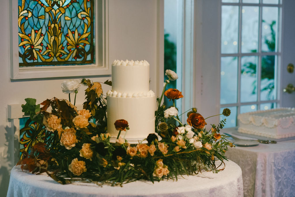 Floral crown around simple 2 tiered white wedding cake