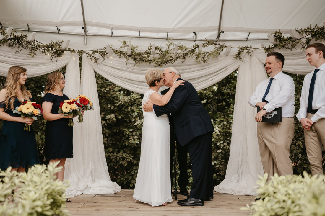 older couple kissing at altar covered by white tent