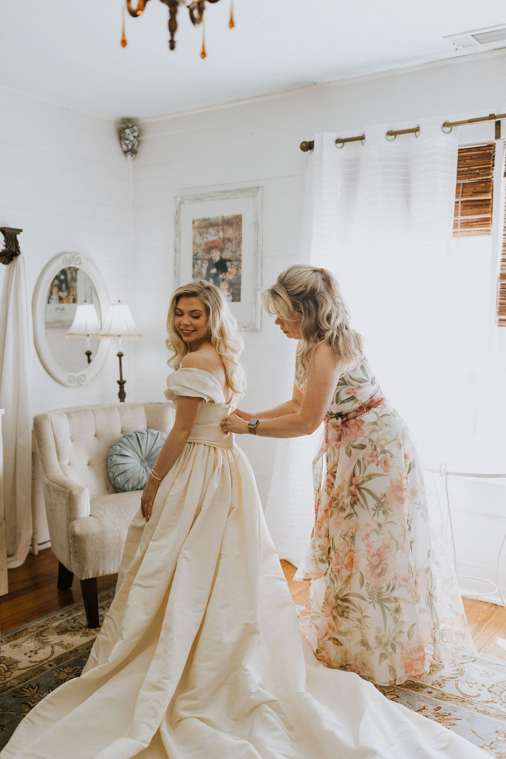 mother buttoning bride's dress in elegant bridal suite