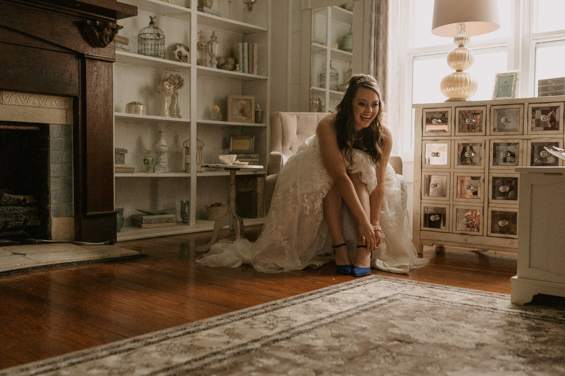 bride putting on blue heels in farmhouse room
