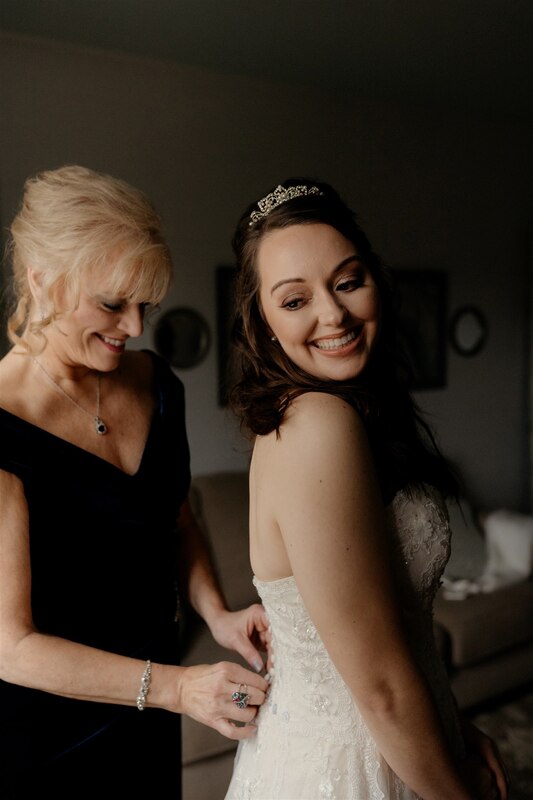 mother helping bride with dress
