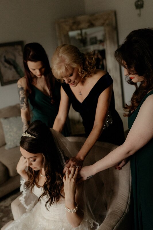 bridesmaids praying over bride in farmhouse getting ready room