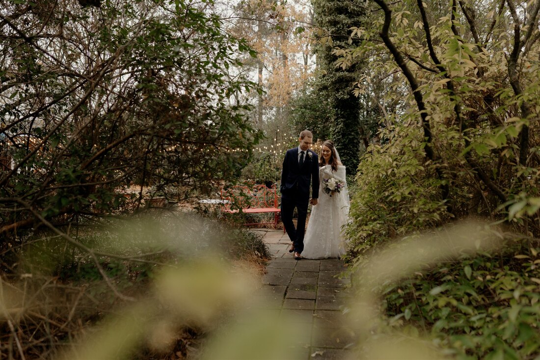 groom and bride walking through gardens