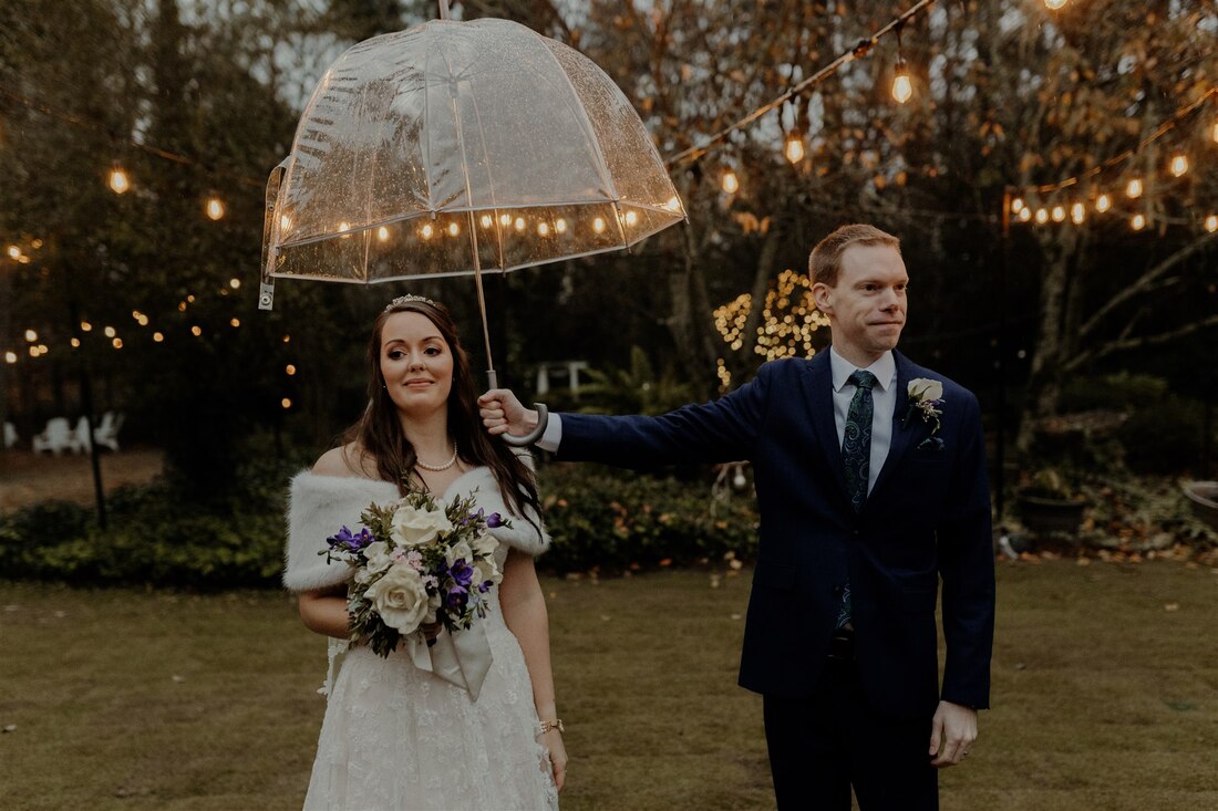 groom holding umbrella over bride
