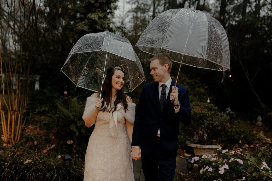 bride and groom holding hands under clear umbrellas