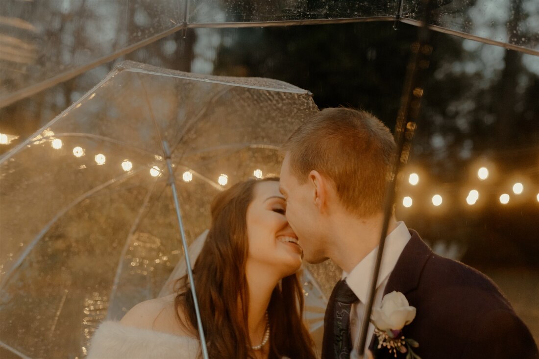 bride and groom under clear umbrellas