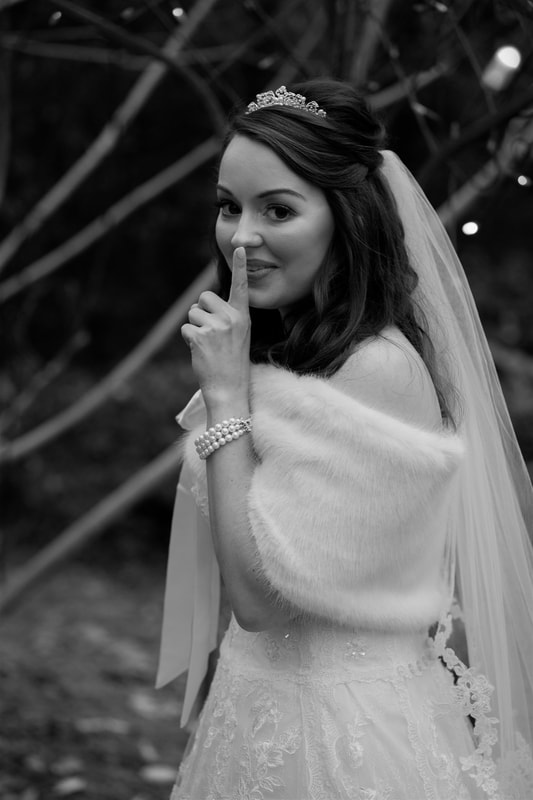 bride holding finger up to lips before first look