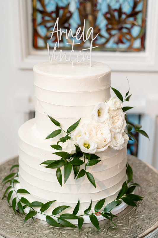 white wedding cake with greenery and white flowers