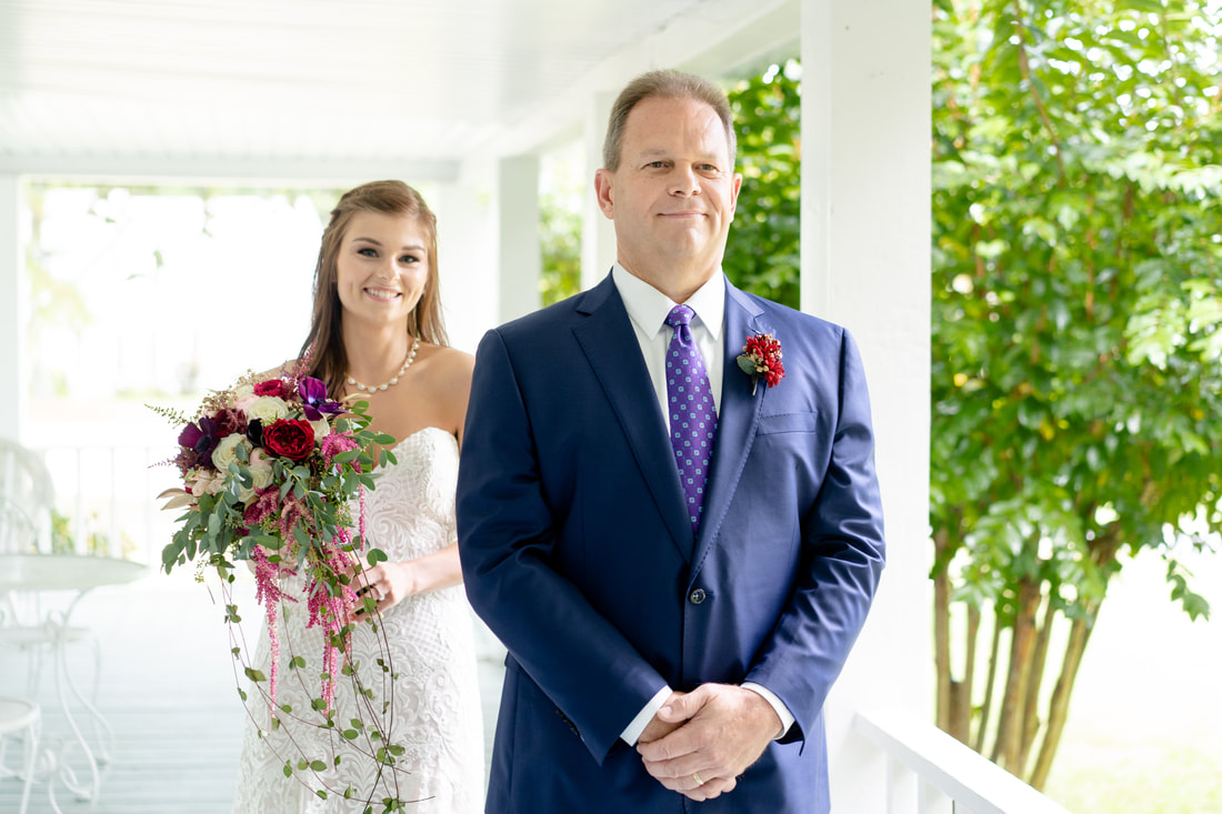 bride standing behind dad on farmhouse wraparound porch before first look