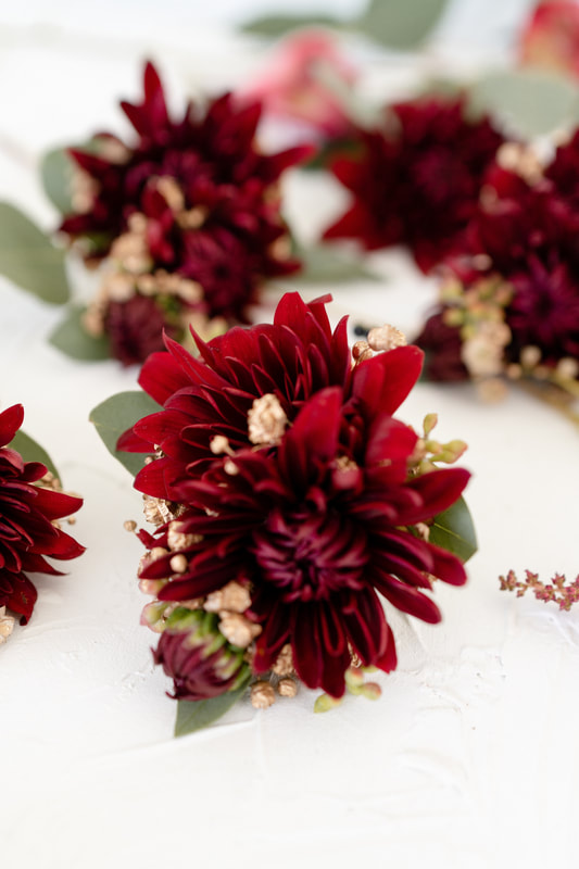 boutonniere made with burgundy flower and dried baby's breath
