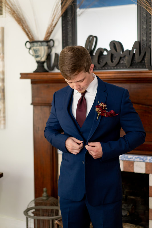 groom in navy suit with burgundy tie, pocket square, and boutonniere