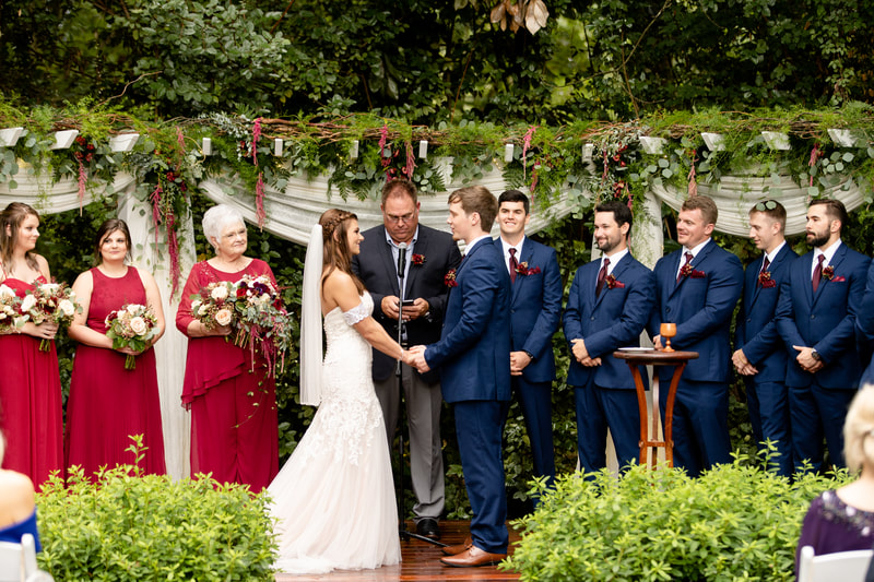 Maroon and navy outdoor ceremony altar with greenery