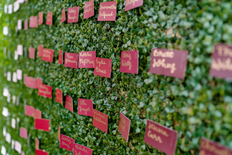 wedding guests' names written on paint chips against greenery wall