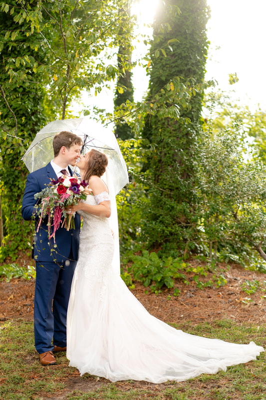 september wedding couple about to kiss under clear umbrella surrounded by ivy