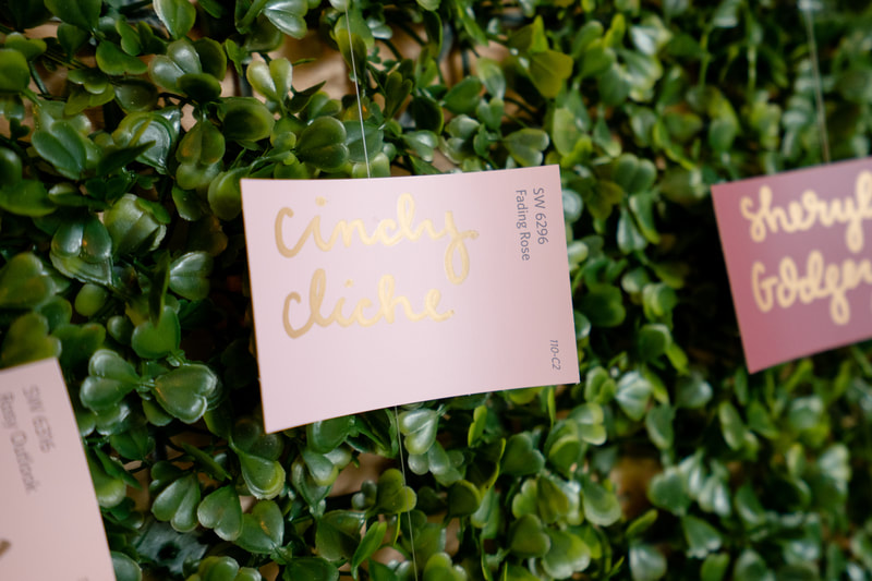 guest's name written on pink paint chip against greenery wall