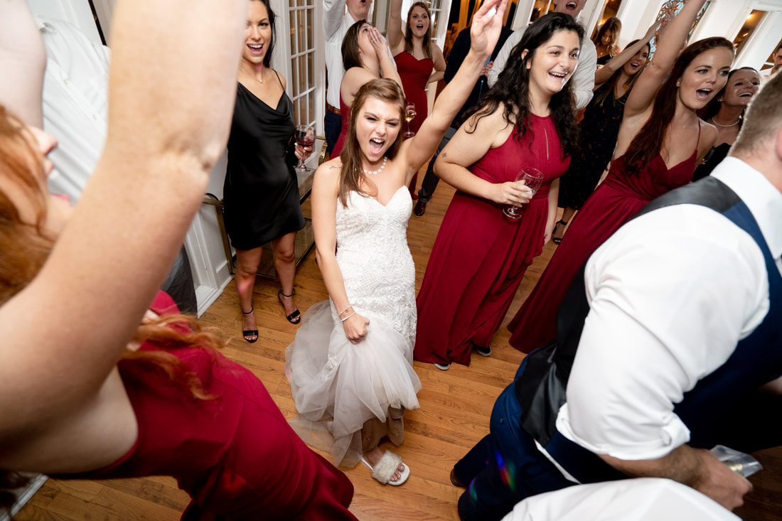 bride dancing surrounded by bridesmaids and guests in carriage house