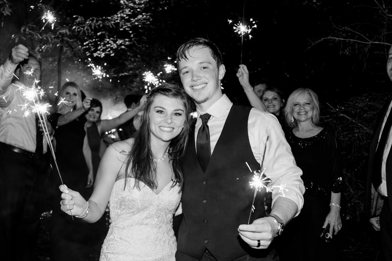 black and white photo of bride and groom holding sparklers during sparkler grand exit