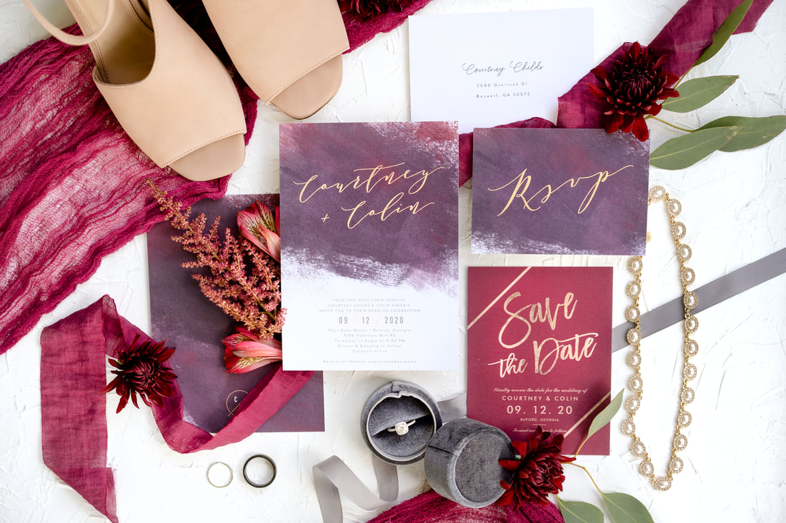detail photo with burgundy, purple, and gold ribbon, florals, and invitation set