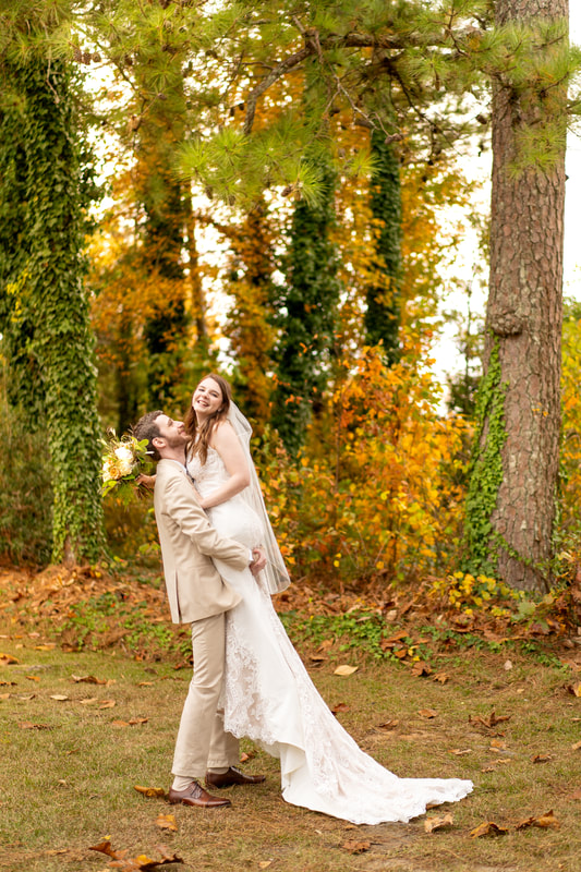 groom picking up bride among fall trees