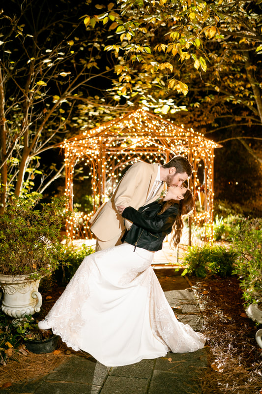 bride and groom kissing in front of gazebo at night