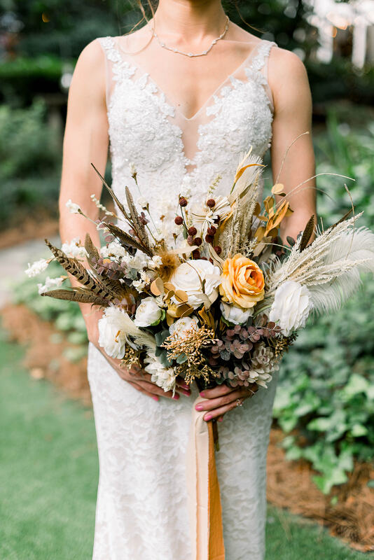 bride with boho bouquet with feathers, pampas grass, and neutral flowers