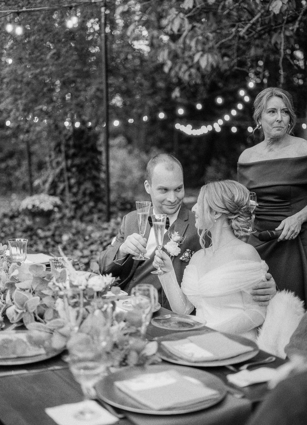 black and white film photo of bride and groom toasting during speech
