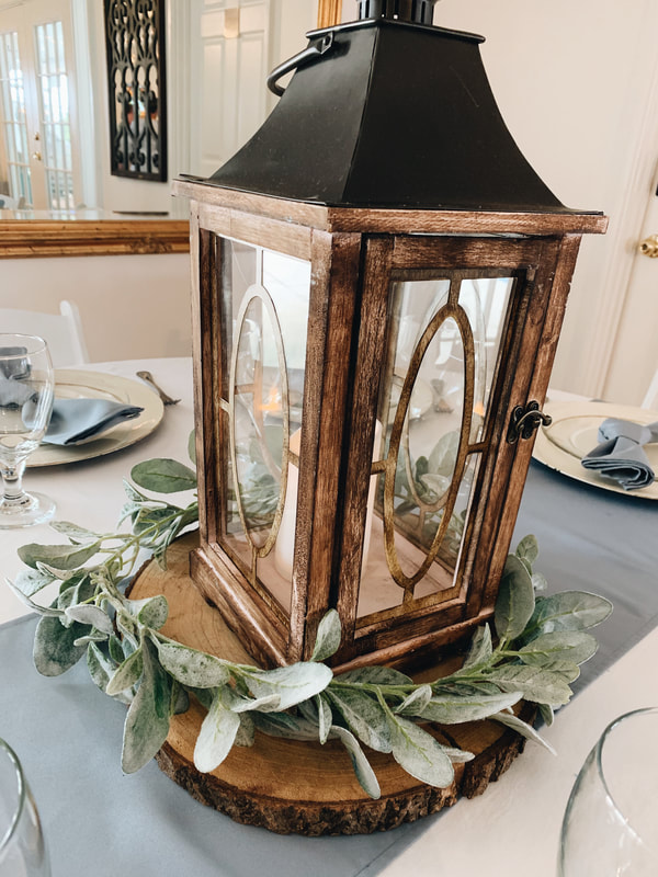 brown wood lantern on wood slice with lambsear greenery as centerpiece