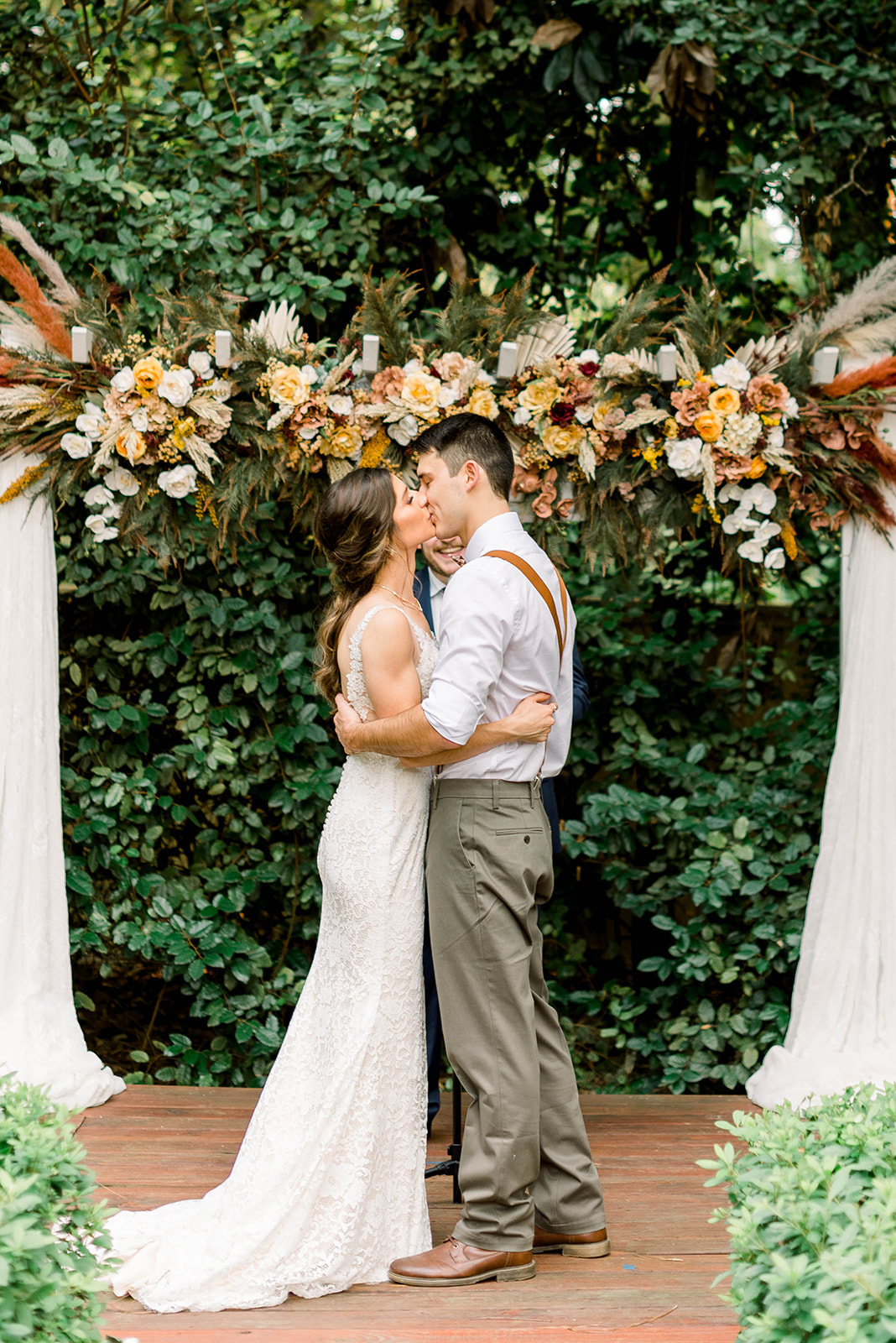 bride and groom kissing in front of bohemian garden altar