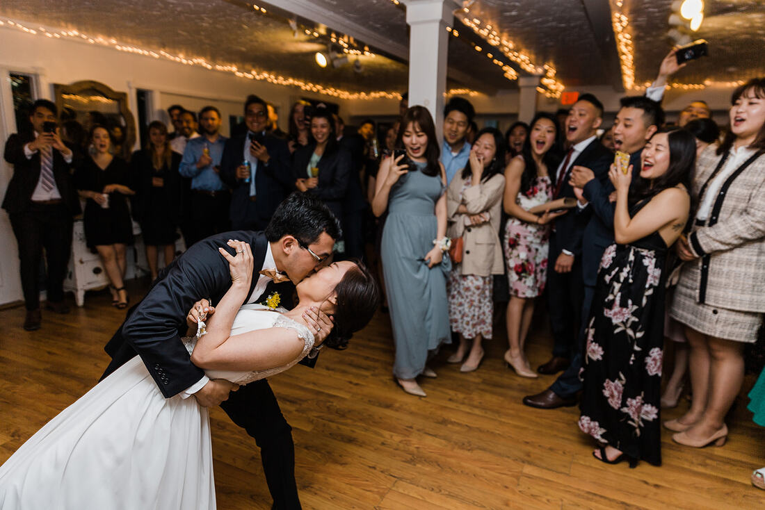Picture of Haeun and Chris sharing a kiss on the dance floor as their guests watch and cheer along.