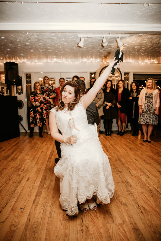 bride makes face and holds up groom doll during shoe game