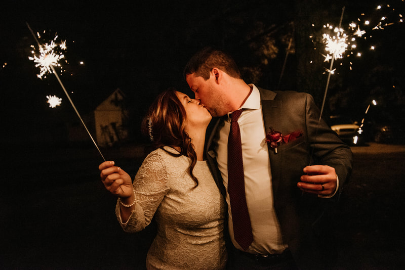 newlyweds kissing and holding sparklers before grand exit