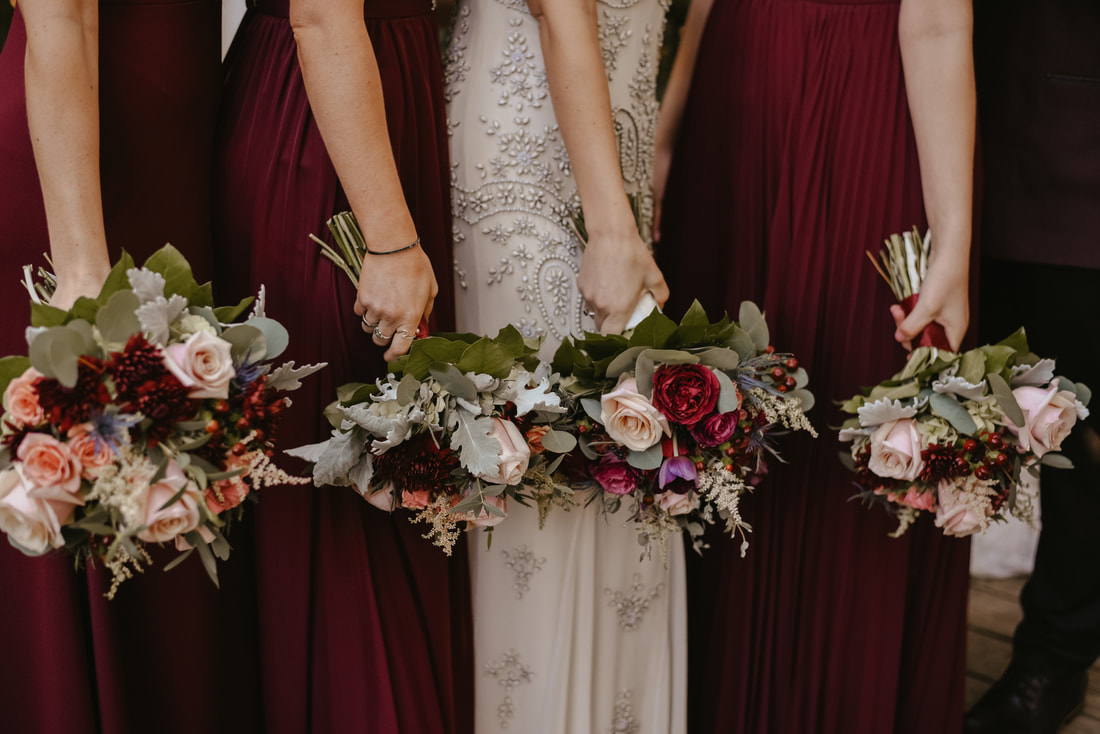 Bride in vintage dress and bridesmaids in deep red dresses with matching bouquets