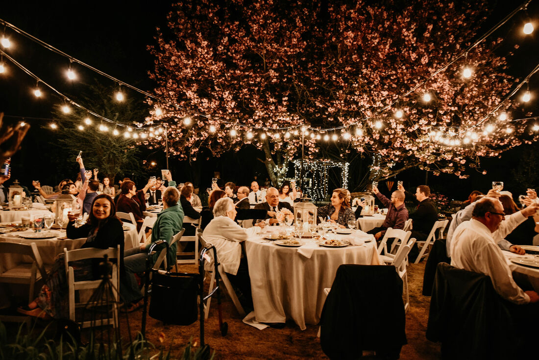 Wedding guests holding up glasses for a toast at night under lights.