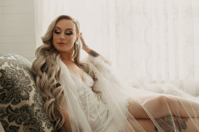 bride in sheer feathered robe posing on chaise lounge
