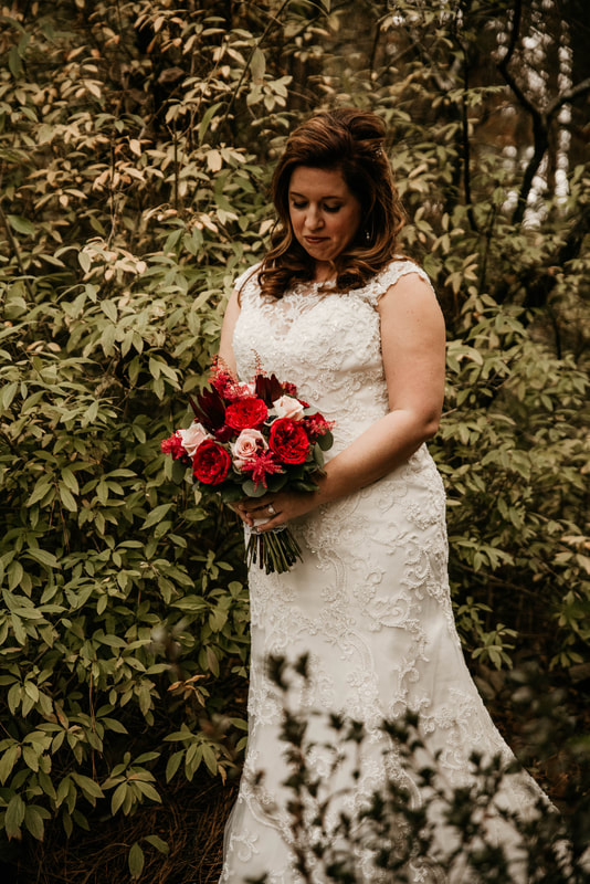 bride poses with full bouquet with roses and eucalyptus leaves