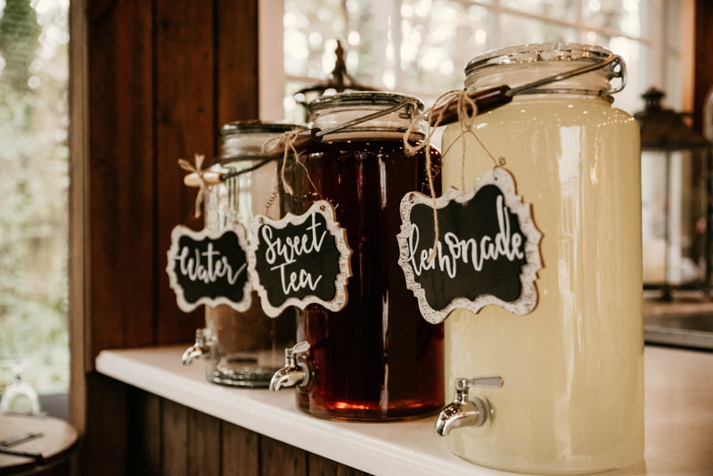 large glass drink containers with sweet tea, water, and lemonade with chalkboard signs
