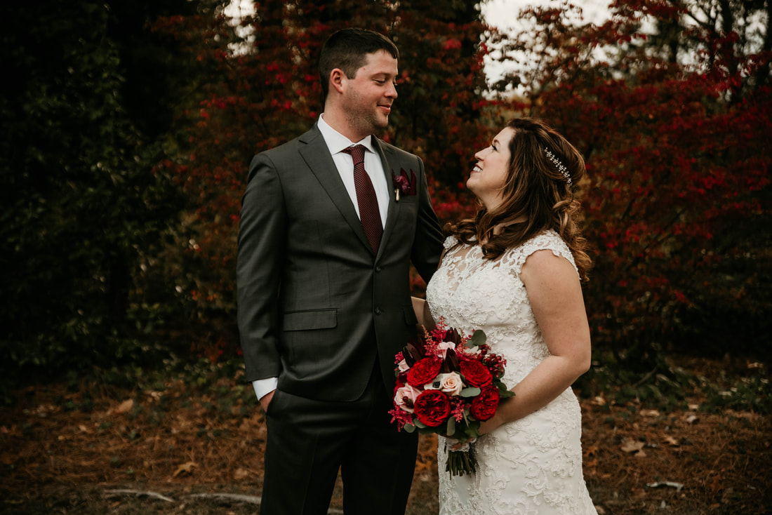 Moody fall wedding with bride in all-lace gown and groom in gray suit with a burgundy tie.