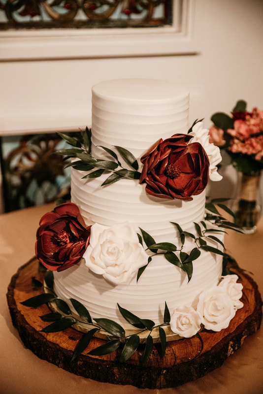 3-tier wedding cake with white and red flowers and greenery