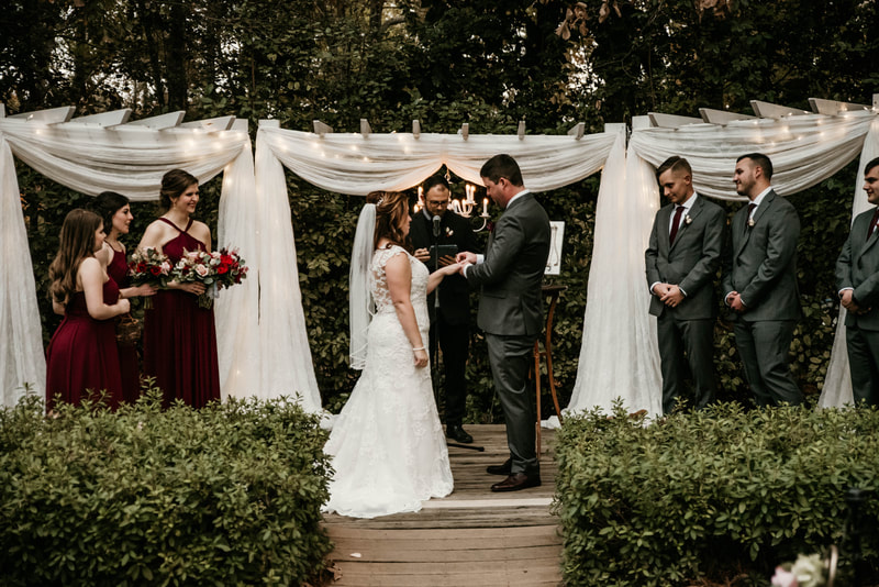 groom putting ring on bride's finger during outdoor fall wedding ceremony