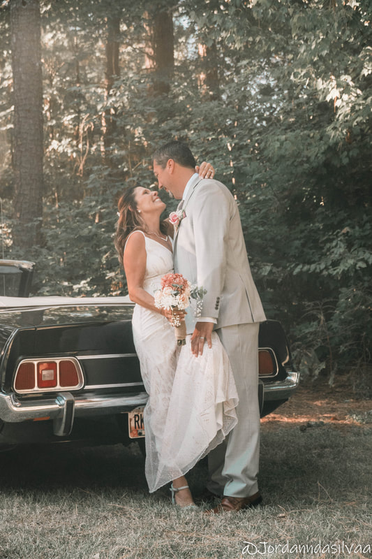 groom and bride posing in front of classic car for post-ceremony photos