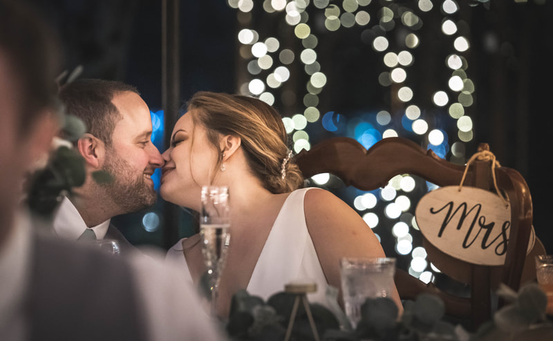 bride and groom kissing at night in an outdoor garden with twinkle lights.