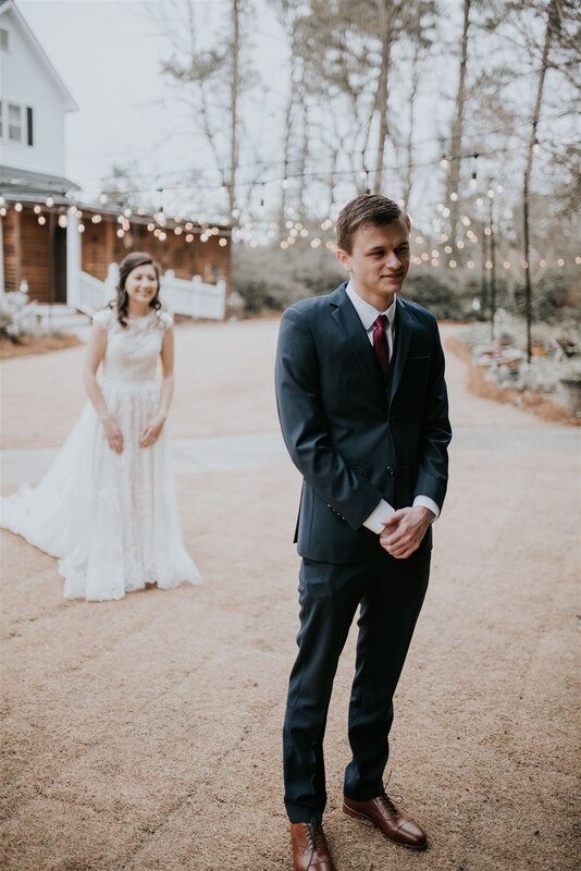 bride standing behind groom for first look