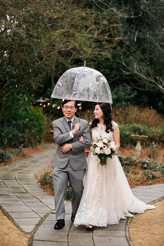 bride walking with dad under clear umbrella