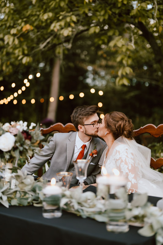 bride and groom kissing at sweet heart table